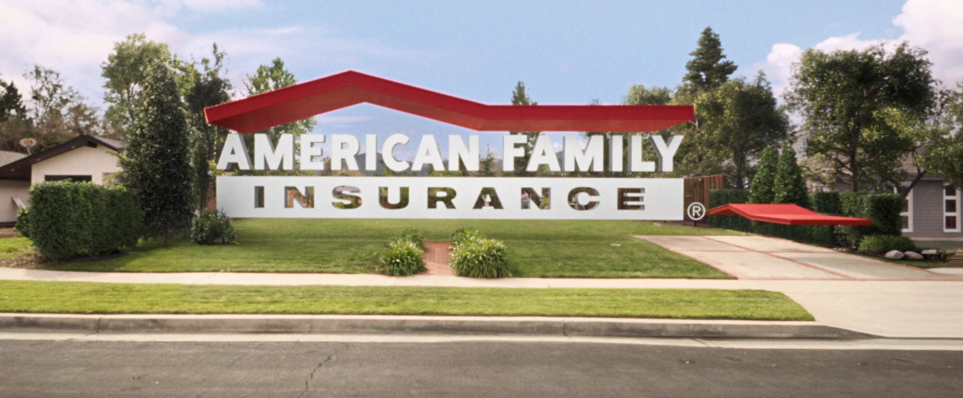 American Family Insurance's CG logo replaces a house in the suburbs. A matching car in the shape of a red roof is in the driveway.