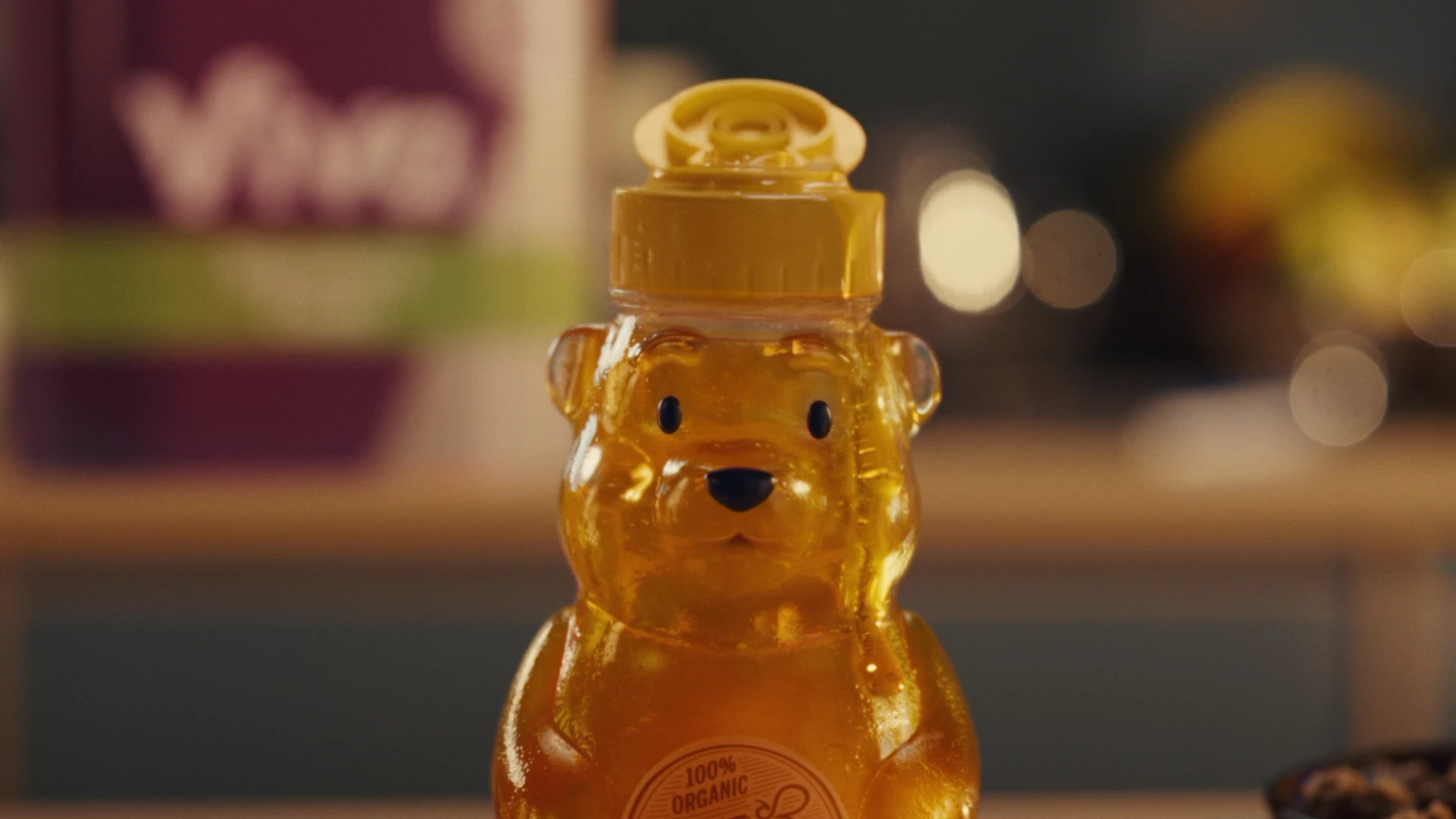 Close-up of a realistic CG bear-shaped honey bottle with honey dripping off of its cap.