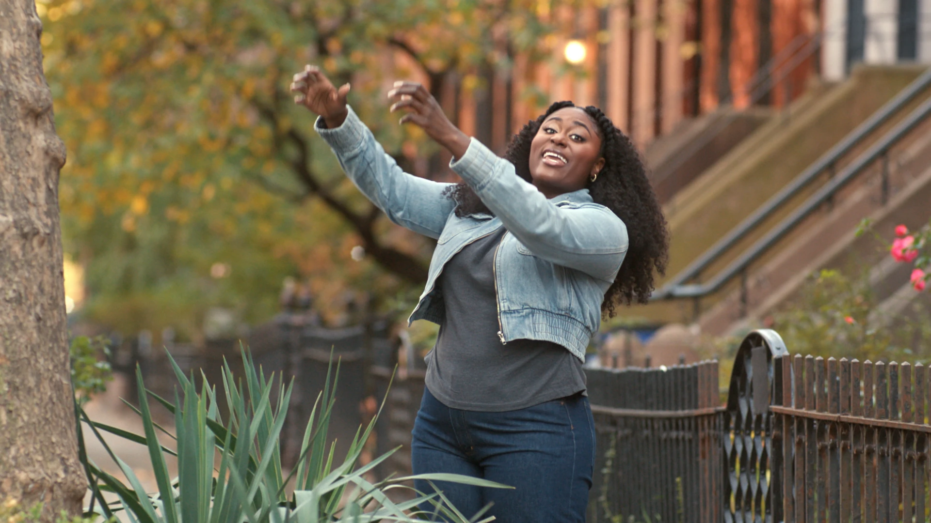 Danielle Brooks is extending her arms towards the top of a tree.