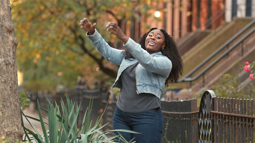 Danielle Brooks is extending her arms towards the top of a tree.